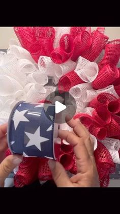 someone is making a patriotic wreath with red, white and blue mesh flowers on it