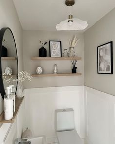 a white toilet sitting in a bathroom next to a shelf filled with vases and pictures