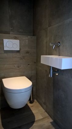 a white toilet sitting in a bathroom next to a wall mounted faucet and sink