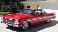 an old red car parked in front of a house