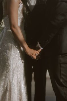 a bride and groom holding hands in front of each other while standing next to each other