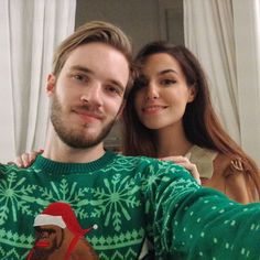 a man and woman taking a selfie in front of a window with christmas sweaters on