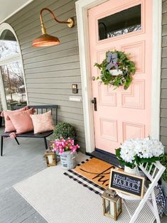 the front porch is decorated with pink and white flowers, potted plants, and a welcome sign