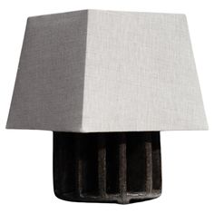 a lamp that is sitting on top of a white table cloth covered base with two black bars sticking out of it