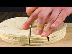 a person cutting into tortillas on top of a wooden table with a knife