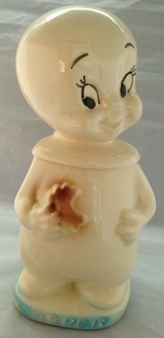 a white ceramic figurine with eyes and hands holding a piece of food in it's mouth