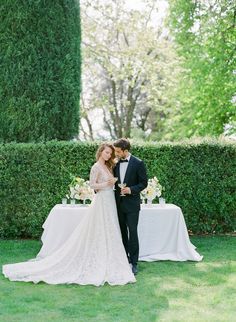 a bride and groom standing in front of a table