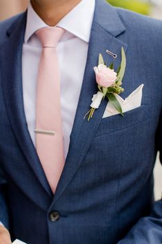 a man in a blue suit with a pink tie and rose boutonniere