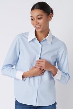 Kal Rieman Classic Tailored Shirt in Oxford Blue on Model Looking Down Cropped Front View Elegant Blue Tops With Striped Collar, Blue Dress Shirt With Striped Collar For Work, Classic Shirt With Cuffed Sleeves And Collar, Classic Tops With Cuffed Sleeves And Collar, Classic Button-up Top With Contrast Collar, Blue Shirt With Cuffed Sleeves And Spread Collar, Blue Tops For Work With Fold Down Collar, Blue Cuffed Sleeves Top For Office, Blue Collared Top With Cuffed Sleeves