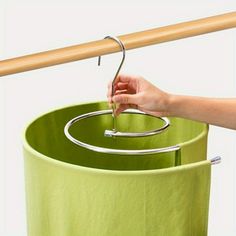 a person is holding a metal object over a green container with a wooden stick sticking out of it