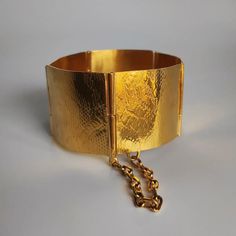 Brazalete fabricado a mano con textura que emula la piel de serpiente. Base de latón y un baño de oro amarillo o rosa (1 mcr). Las medidas pueden variar ligeramente. Ancho: 3 cm Largo estirado: 18 cm