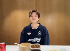 a boy sitting at a table with food and drinks