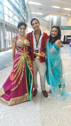 two women and a man dressed up in costume posing for a photo at an airport