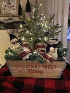 a small christmas tree in a wooden crate with lights on the branches and snowmen