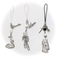 three different necklaces with charms attached to them on a white surface, one has an angel and the other has a swan