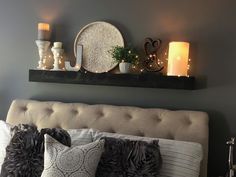 a bed topped with pillows and candles next to a wall mounted shelf filled with decorative items