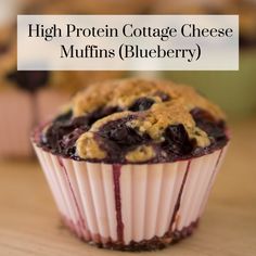 a close up of a muffin on a table with blueberries in the background