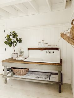 a white sink sitting on top of a wooden table next to a potted plant