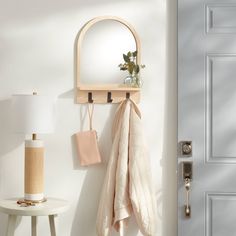 a white door with a mirror and coat rack on the wall next to a table