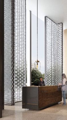 an office lobby with two people standing in front of the reception desk and glass partitions