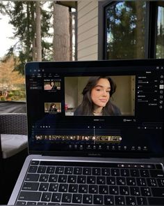 a laptop computer sitting on top of a wooden table next to a glass door and window