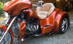 an orange motorcycle parked in front of a garage with a dog seat on it's side