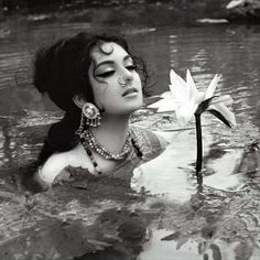 a woman floating in the water next to a white flower