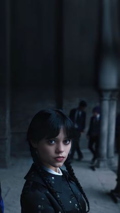 a woman with braids standing in an old building looking at the camera and staring into the distance