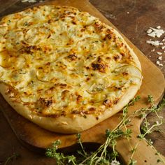 a pizza sitting on top of a wooden cutting board next to some herbs and seasoning