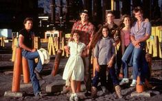 a group of people standing next to each other in front of an industrial area with pipes