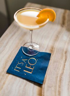 a glass filled with liquid sitting on top of a wooden table next to a blue napkin