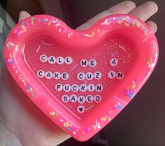 a pink heart shaped cake tray with words written on it in white letters and sprinkles