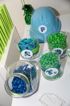 there are many candy in bowls on the table with blue and green candies around them