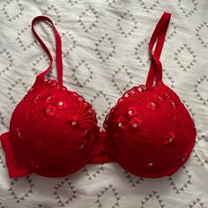 a red bra that is laying on a white sheet with diamond embellishments