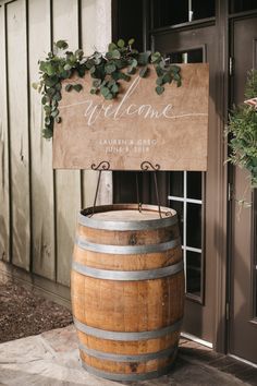 a welcome sign is placed on top of a wooden barrel as it sits in front of a door