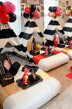 a room filled with lots of black and white striped tents covered in red and gold balloons