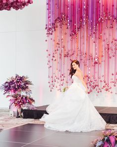 a woman in a wedding dress is standing on the stage with flowers and decorations behind her