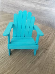 a miniature blue chair sitting on top of a wooden table