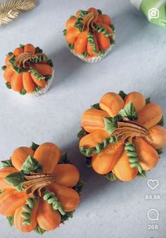 three cupcakes decorated with orange flowers and green leaves on a white counter top