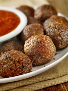 some meatballs are on a plate with dipping sauce in the bowl next to it