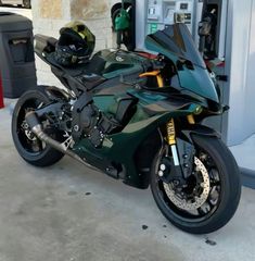 a green motorcycle parked in front of a gas pump