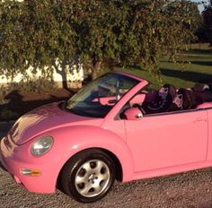 a pink convertible car parked in front of a house