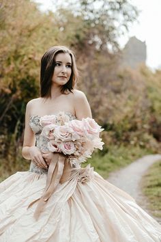 a woman in a wedding dress holding a bouquet of flowers and posing for the camera