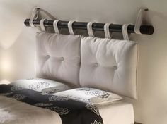 there is a bed with two pillows on the headboard and an iron rail above it