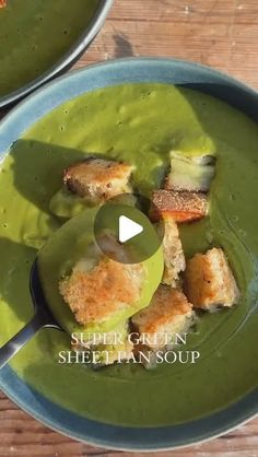 two bowls filled with green soup and croutons on top of eachother