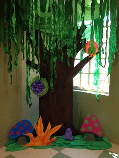 a tree with paper flowers and leaves on the ground in front of a classroom wall