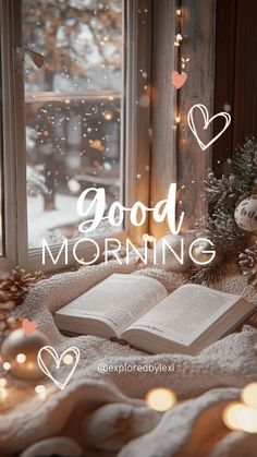 an open book sitting on top of a blanket next to a window with the words good morning