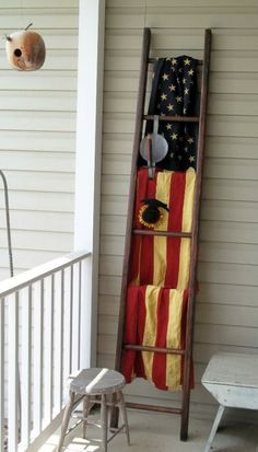 an old ladder is decorated with american flag and sunflowers on the front porch