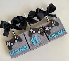 three cupcake toppers decorated with video game controllers and bows are on the table