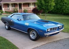 a blue muscle car parked in front of a house